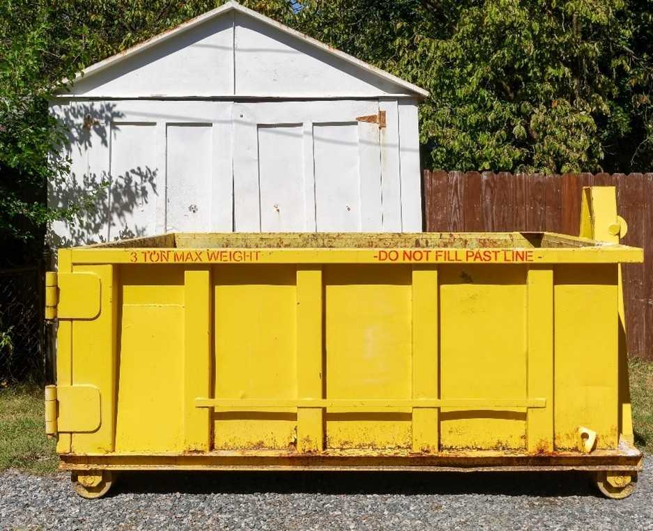 Yellow dumpster container for debris removal outside shed, junk hauling service in Acworth, GA, for residential waste cleanup bin.