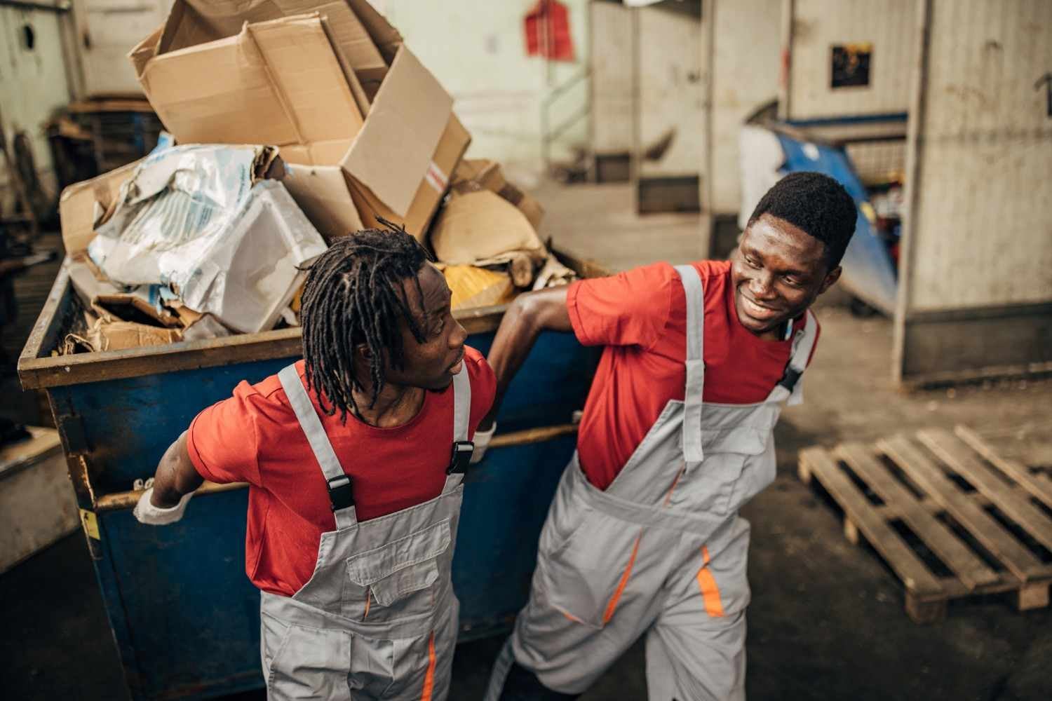 Workers loading a dumpster with waste materials during a cleanup project in Dallas, GA