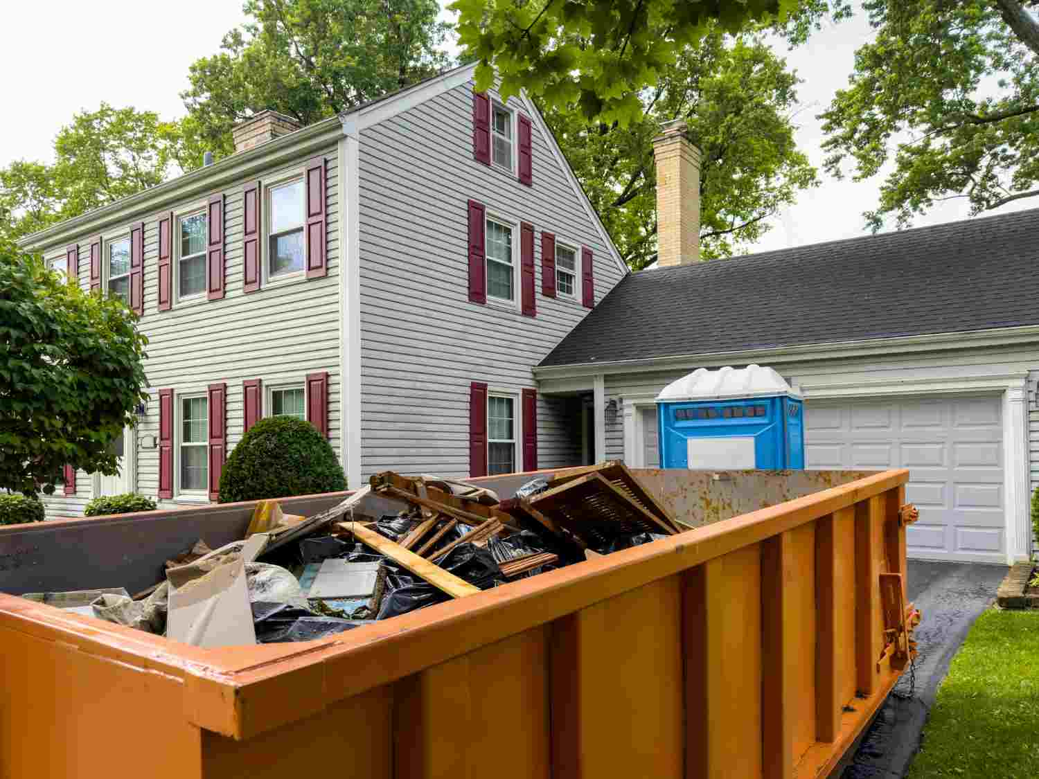 Orange dumpster filled with household debris outside a home in Acworth, GA