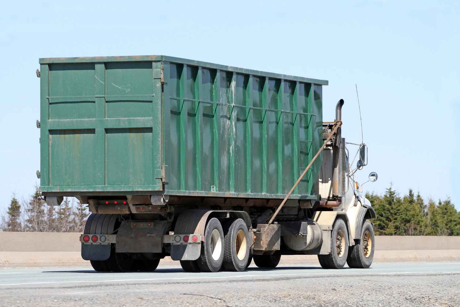 Roll off dumpster truck transporting a large waste container in Dallas, GA